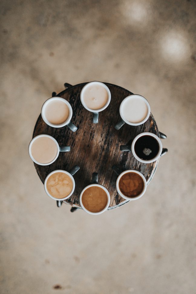 A circle of coffee cups on a wood table.