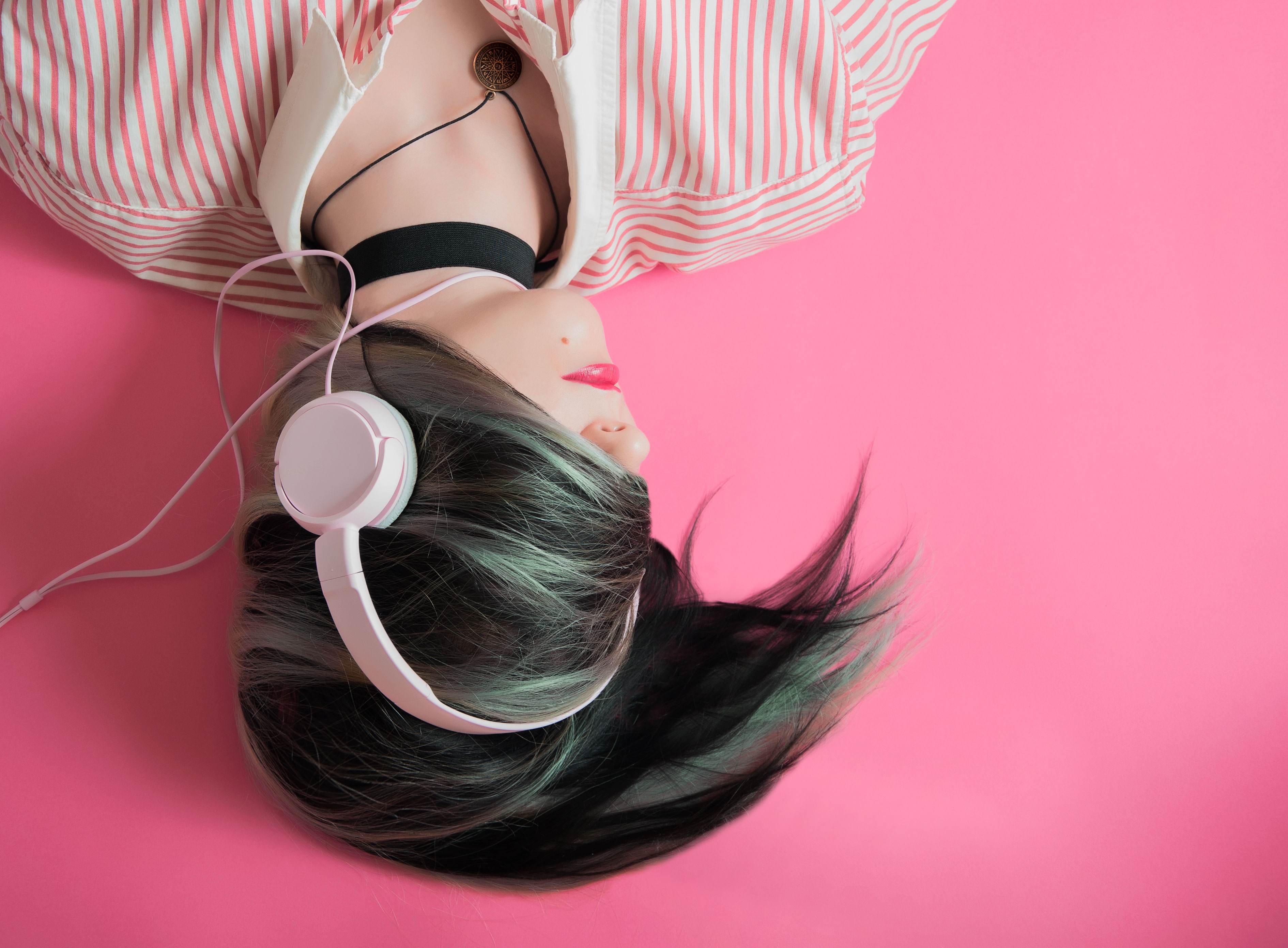 Person with headphones against a pink background